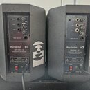 Dva šedé aktivní reproduktory značky Montarbo, model MT150 - A. Na zadním panelu je nápis PROCESSOR CONTROLLED POWERED MONITOR a označení MADE IN ITA…