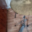 Fotografie zachycuje mosazný činel namontovaný na kovovém stojanu. Na pedálu stojanu je viditelné logo CB a nápis CYMBALS. Povrch činelu vykazuje zná…