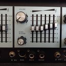 Detailní pohled na ovládací panel elektronického zařízení s několika kanály. Jsou zde vidět posuvníky, otočné knoflíky a vstupy s popisky VOLUME, ECH…