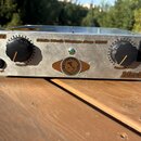 Stříbrný basový zesilovač s nápisem Little Mark Vintage Amp 3000. Na předním panelu jsou dva černé oválné knoflíky s oranžovými značkami nad nápisy L…