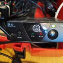 Černý bezdrátový přijímač s nápisy SR 40 STATIONARY RECEIVER a MINI PRO. Na předním panelu je logo AKG, ovladač VOLUME, kontrolky RF OK a AF CLIP a v…