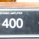 Černý rackový stereo zesilovač s bílými nápisy. Na předním panelu je uveden text POWER MOSFET STEREO AMPLIFIER a modelové označení M 400. Zařízení má…