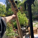 Zadní strana krku a hlavy basové kytary z přírodního dřeva. Na zadní straně hlavy je vidět logo v trojúhelníku a nápis "Handmade". Nástroj má čtyři č…