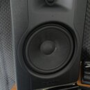 Černý studiový monitor s dvěma reproduktory umístěný na černém stojanu. V dolní části přední mřížky je vyražen nápis M-AUDIO BX. Povrch je matný, s v…