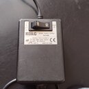 Černý síťový adaptér s napisem KORG AC/AC POWER SUPPLY KA169E. Na štítku jsou uvedeny údaje MODEL: T57A-9-3000-3, PRI: 230V~50Hz 155mA, SEC: 9V~3000m…