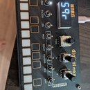 Černý elektronický přístroj s texturovaným povrchem a bílými tlačítky. Na panelu jsou nápisy KORG, digital mkII a označení ovládacích prvků: OSC, FIL…