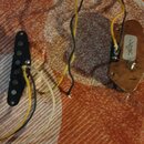 Černý elektrický snímač s šesti póly a připojenými vodiči v žluté, černé a bílé barvě. Vedle něj je umístěn hnědý plastový kryt elektroniky s vnitřní…