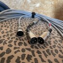 Šedý kabel s třemi konektory, položený na podložce s leopardím vzorem. Na levé straně je jeden samice konektor a vpravo dva samce konektory s kovovým…