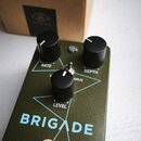 Kytarový efekt pedál v olivově zelené barvě s nápisy BRIGADE a UAFX CHORUS & VIBRATO. Zařízení má tři černé ovládací knoflíky s popisky RATE, DEPTH a…