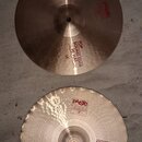 Dva mosazné činely typu hi-hat v barvě zlaté. Horní činel nese červený nápis PAISTE 2002 a černý text TOP SOUND EDGE HI-HAT 14". Dolní činel má nápis…
