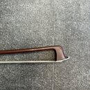 Detailní pohled na hrot smyčce z tmavého dřeva. Na konci hůlky je vidět bílá koncovka a napnutý smyčec s bílými vlasy. Povrch dřeva vykazuje drobné š…
