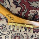 Záběr na hlavu dřevěné kytary s šestnáctmi zlatými ladičkami a bílými knoflíky. Na dřevě je vidět logo Epiphone s nápisem Gibson USA customs a sériov…