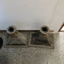 Dvě šedé, pyramidovitě tvarované akustické trouby z plastu nebo kompozitního materiálu. Povrch je znečištěný prachem a v horní části každé trouby je…