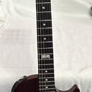 Tmavě červená elektrická kytara typu Les Paul s černým hmatníkem a dvěma humbuckery. Na hlavě je bílý nápis Gibson a pod ním kurzívou Les Paul Model.…