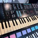 Černý digitální klávesový nástroj s nápisem Musicstation. Horní panel obsahuje množství tlačítek, posuvníků a červený digitální displej s hodnotami 8…