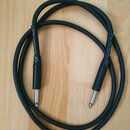 Černý instrumentální kabel s 6,3mm jack konektory na obou koncích. Na obou gumových krytech konektorů je bílý nápis „PV series by K&M“. Kabel je svin…