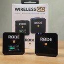 Na fotografii je bezdrátový mikrofonní systém RØDE Wireless GO v originálním bílém balení. Sada obsahuje dva černé čtvercové vysílače a přijímač s ná…