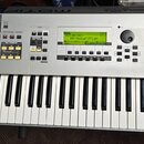 Stříbrný digitální klavír s logem YAMAHA v levém horním rohu a nápisem MOTIF 7 v pravé horní části. Nástroj má bílé klávesy, černé klávesy a ovládací…