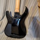 Zadní strana elektrické kytary s černým lesklým povrchem korpusu a světle hnědým dřevěným hmatníkem. Nadesítkovém krytu krku je nápis "Custom Shop" a…