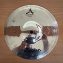 Kruhový mosazný činel typu splash s viditelným opracováním povrchu. Na horní části je nápis A CUSTOM SPLASH 10"/25 cm a ve spodní části logo Zildjian…