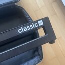 Detailní pohled na černý plastový stojan s bílým nápisem classic PRO. Předmět má obdélníkový tvar s výřezem uprostřed a je umístěn v otevřeném černém…