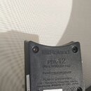 Černý trigger pad s nápisy Roland, PDX-12 a DUAL TRIGGER PAD. Na štítku je uvedeno Roland Corporation, adresa v Japonsku a sériové číslo T4P6483. Dol…