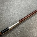 Detailní pohled na část hrdla nebo tBodies nástroje z tmavého dřeva. Je zde vidět stříbrný kovový kroužek s vryty a černý úchop z kůže nebo syntetick…