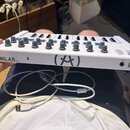 Bílá MIDI klaviatura s nápisem MINILAB mkII. Na horní straně se nachází osm otočných knoflíků a několik posuvníků. Na boku je vidět logo Arturia, USB…