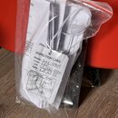 Průhledný plastový sáček s několika papíry a dokumenty, který leží na červeném povrchu. V popředí je vidět bílá karta s nápisem INSPECTION CARD, kde…
