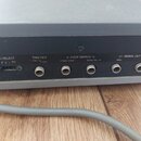 Záběr na zadní panel šedého elektronického zařízení s černým kovovým povrchem konektorů. Jsou zde vidět nápisy TRIG SELECT, TRIG OUT +5V GND, FOOT SW…