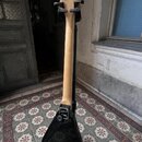 Elektrická kytara s černým bodies ve tvaru V a světlým dřevěným hmatníkem a hlavou. Na spodní části krku je viditelné logo B.C. Rich. Kytara je umíst…