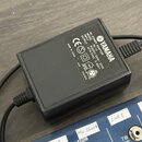 Černý síťový adaptér značky YAMAHA s nápisem AC POWER ADAPTOR a označením modelu PA-10V. Na štítku jsou uvedeny technické parametry INPUT: AC230V 50H…