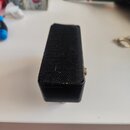 Černý kytarový efekt pedál s obdélníkovým tvarem. Horní plocha je pokryta černou texturovanou povrchovou úpravou, na které jsou vidět drobné škrábanc…