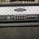 Černý kytarový zesilovač s horním stříbrným panelem s reliéfním vzorem. Na panelu je nápis TRIPLE XXX a logo Peavey s textem Made in USA U.S.A. a Ult…