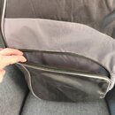 Černý textilní obal s šedým pruhem a zipovou kapsou. V horní části je žlutý nápis soundsation. Povrch materiálu vykazuje mírné pomačkání.