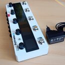 Bílá efektová pedálboard s černým displejem a ovládacími knoflíky. Na boku je nápis EFFECT PLETHORA X5 a pod ním menší text MULTI EFFECTS PROCESSOR.…