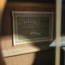 Detailní záběr na štítek uvnitř akustického nástroje z lehkého dřeva. Štítky nese nápisy „Arbor“, „LW400N“ a „MANUFACTURED EXCLUSIVELY FOR a HOHNER“.…