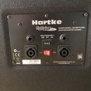 Zadní panel basového komba značky Hartke, model HyDrive 112. Na černém povrchu je bílý nápis POWER RATING: 300 WATTS RMS NEODYMIUM DRIVER 4/8 OHMS a…