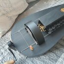 Černý strunný nástroj s oválným korpusem a dlouhým hmatníkem. Na povrchu jsou vidět dva dekorativní vyřezané ornamenty ve tvaru hvězdic. Nástroj má č…