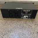 Černý výkonový zesilovač v kovovém šasi s ventilačním mřížkovým otvorem a ventilátorem. Na zadním panelu jsou nápisy CARVIN a B1500, dále texty SPEAK…