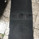 Černý obdélníkový kus tlumícího materiálu nebo podložky s texturou připomínající plst. Povrch vykazuje známky opotřebení, zaprášení a v prostřední čá…