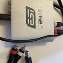 Stříbrné kovové audio rozhraní s nápisem U24XL a logem EST. Zařízení má několik konektorů, do kterých jsou zapojeny černé kabely s červenými a bílými…