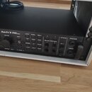 Černý rackový procesor s nápisem Axe-Fx II PREAMP/ FX PROCESSOR umístěný v hliníkovém racku. Přední panel obsahuje ovládací knoflíky, tlačítka s popi…