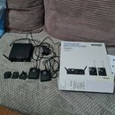 Fotografie zobrazuje bezdrátový systém AKG Wireless System v originální krabici a s příslušenstvím. Na bílém obalu krabice je nápis INSTRUMENT WIRELE…