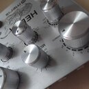 Detailní záběr na stříbrný efektový pedál s kovovým povrchem. Na šasi jsou viditelné nápisy meris, HELIX a CHROMATIC, dále označení MIC OFF a stupnic…