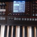 Detailní pohled na ovládací panel a klávesy digitálního klavíru. Na černém povrchu je nápis E-A7 a displej zobrazující seznam zvuků v kategorii Organ…