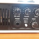 Detail zadního panelu bílého elektronického zařízení s černým ovládacím panelem. Jsou zde tři otočné ovladače s nápisy OUT LEVEL, VOICING a SPACE, vs…