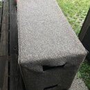 Šedý obal z plsti nebo podobného textilu přes hranatý předmět. Obal má na boční straně dva vyřezané oválné úchyty. Povrch materiálu je rovnoměrně tex…
