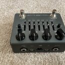 Šedý kytarový efekt pedál s kovovým šasi a dvěma stříbrnými spínači. Na horní straně je nápis MICROTUBES X ULTRA, DISTORTION a BYPASS, v horním okraj…