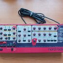 Červený virtuální analogový syntetizátor s nápisem nord rack 2 virtual analog. Na předním panelu jsou umístěny početné ovládací knofíky, tlačítka a n…